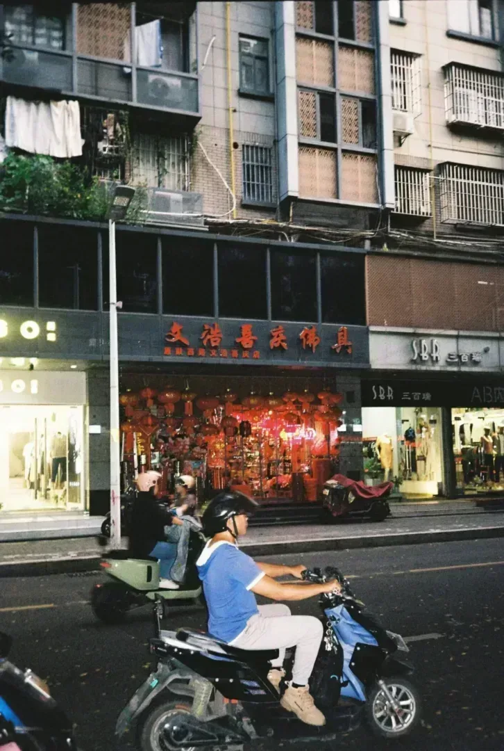 a man riding a motorcycle down a street next to tall buildings